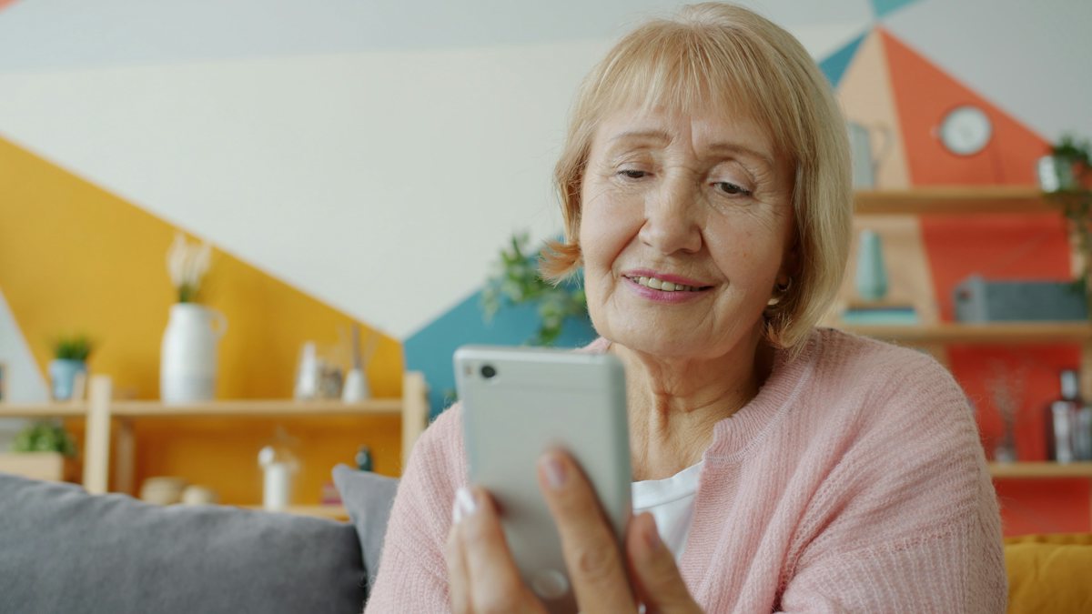 A smiling older woman looking at her phone at home